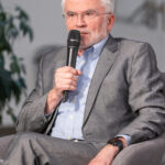 Ein Mann im Anzug sitzt und spricht ins Mikrofon.