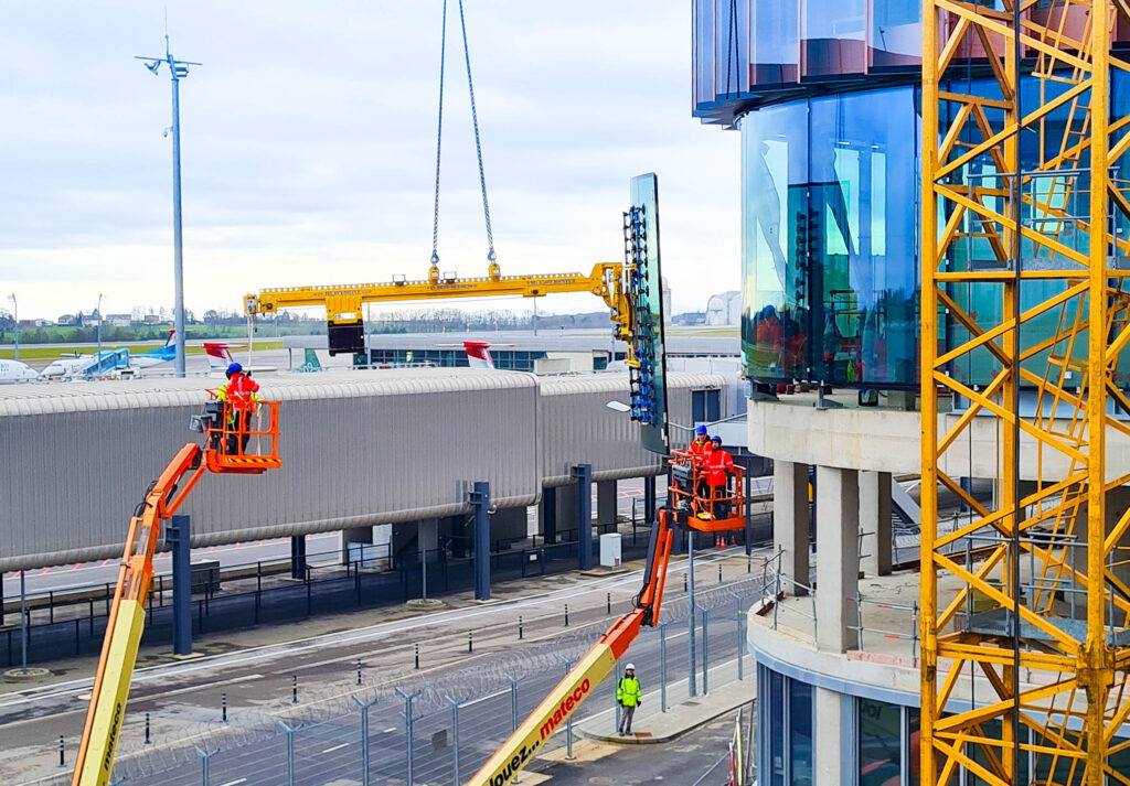 Um die gebogenen Isolierglas-Einheiten unter einem Überstand von 2.602 Millimetern montieren zu können, war der Montagespezialist Heavydrive mit einem Vakuumsaugsystem samt Gegengewichtssystem vor Ort. © Heavydrive