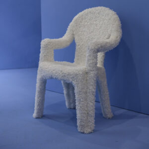 Ein flauschiger weißer Sessel steht in einem blauen Raum.