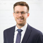 Junger Mann mit Brille im Anzug.