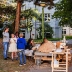 Menschen sitzen draußen auf einer Bank und reden.