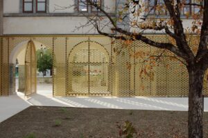 EIn Innenhof mit Baum. Die Fassade ist hell gestalten mit Bögen.