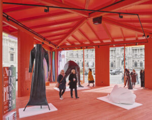 Ein roter Raum mit Skulpturen, darin gehen Menschen.