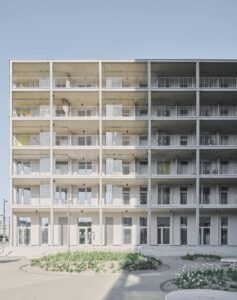 Ein modernes mehrstöckiges Haus mit Balkonen als Fassade. Das haus ist weiß und hat ein Flachdach.