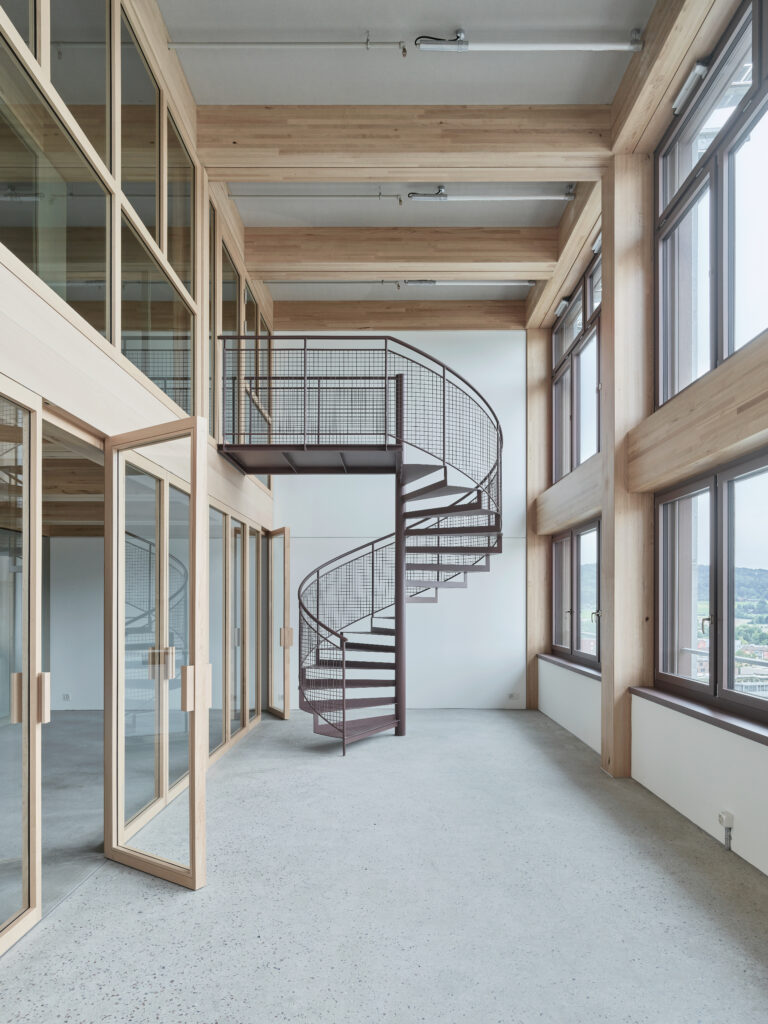 Ein moderner Innenraum über Zwei Stöcke. Sie werden durch eine Wendeltreppe verbunden.