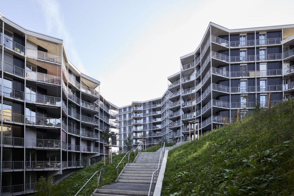 Ein großer skulpturaler Wohnbaukomplex mit grünem Außenbereich.