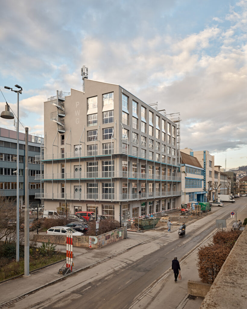 Ein mehrstöckiger Neubau neben einer Straße.