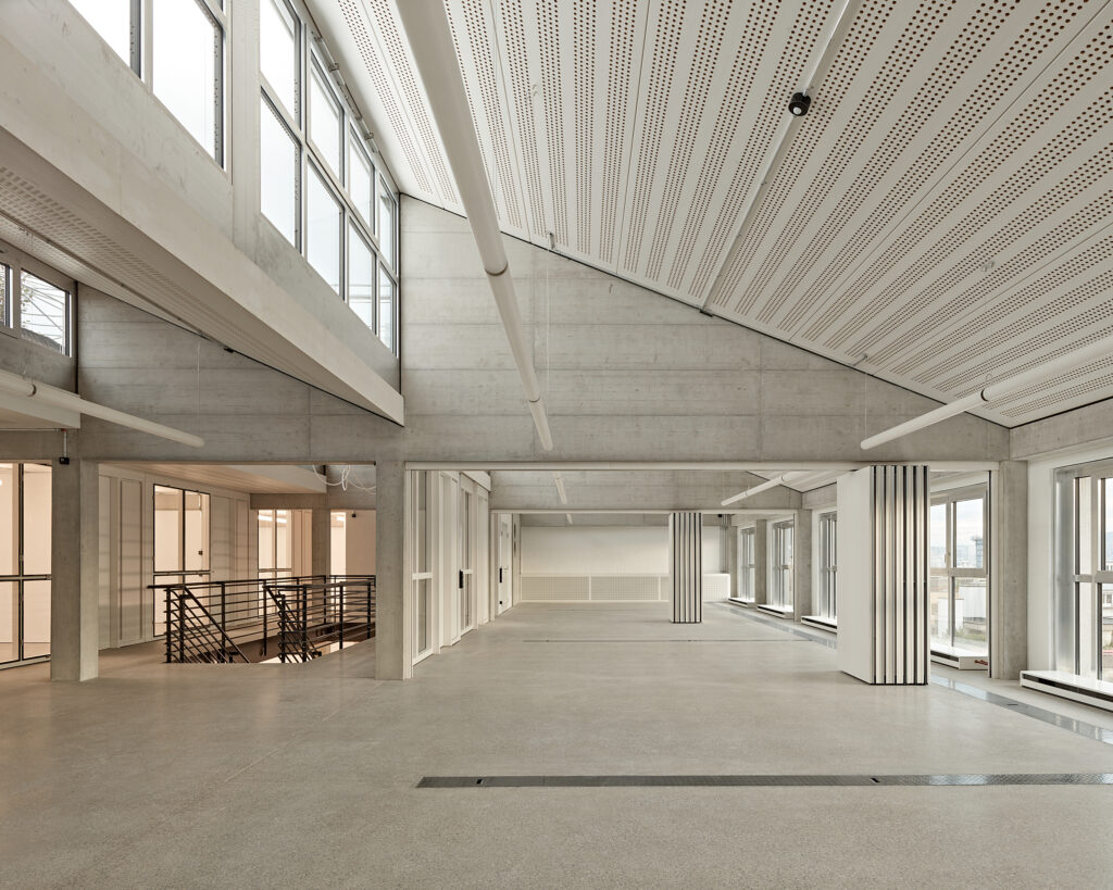 Ein heller, moderner, weißer Innenraum der dich durch Säulen und einer Oberlichte auszeichnet.