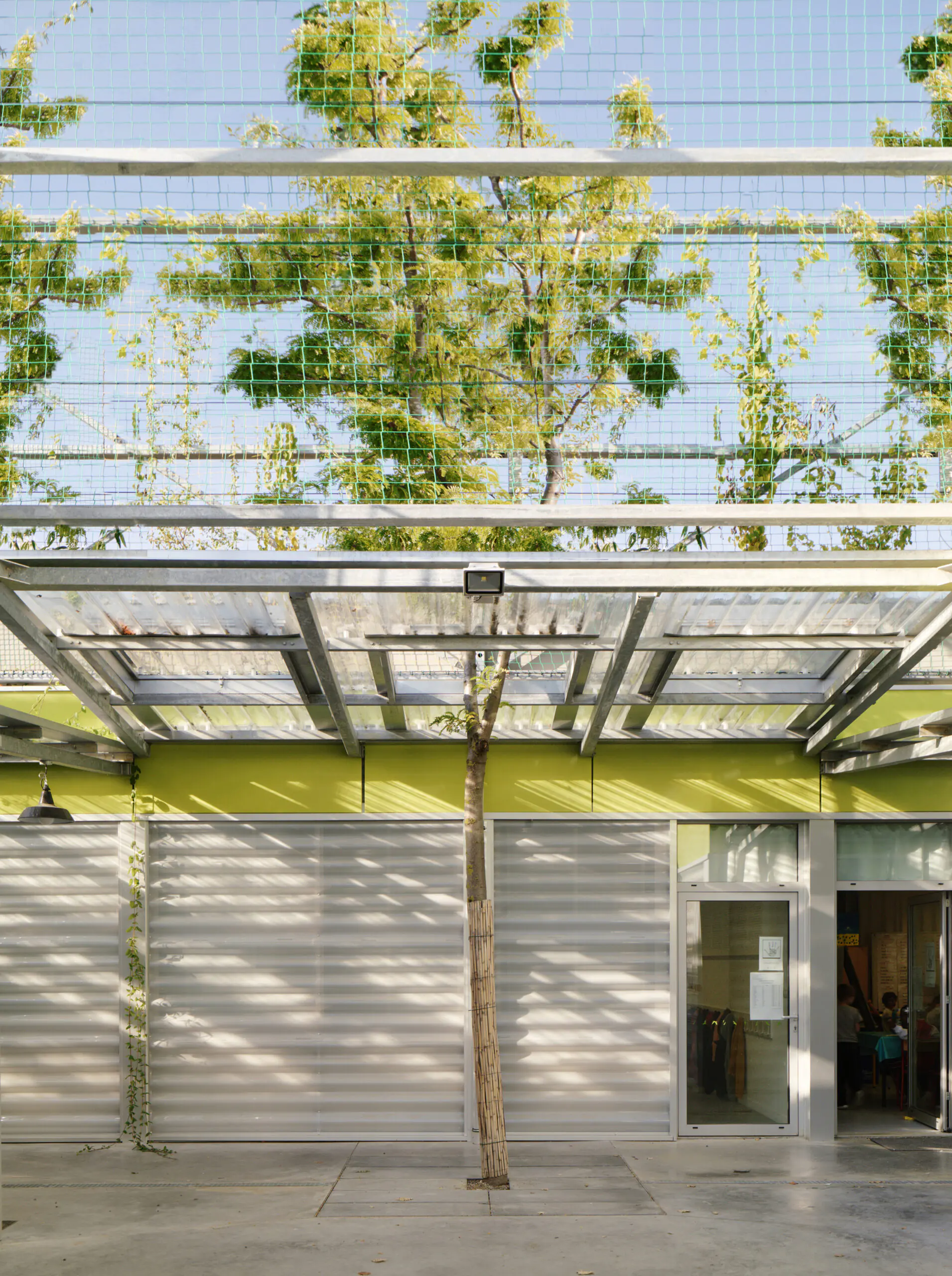 Der Schulbau in Frankreich setzt neue Maßstäbe für nachhaltige Architektur im Kontext des Klimawandels. Mit der Integration von 500 über 9 Meter hohen Bäumen entsteht ein Mikroklima, das die Umgebungstemperatur um mehr als 3°C senkt. Die Bäume sind dabei nicht nur Teil der Landschaft, sondern auch ein integraler Bestandteil der Architektur : Unterrichtsräume und Wege sind um die Bäume herum, darunter und dazwischen angeordnet. Die Schule wird so zu einem lebendigen Lernraum, der Kinder aktiv in das Zusammenspiel von Architektur und Natur einbezieht.