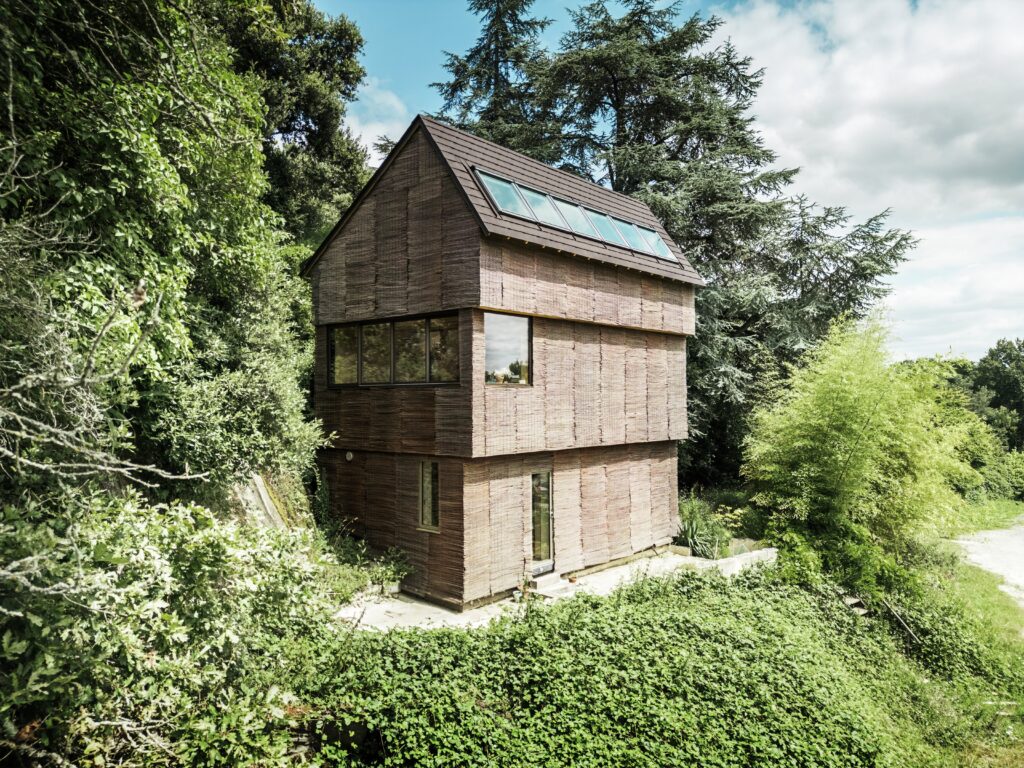 Gedeckt ist das asymmetrisch geneigte Satteldach mit Prefa-Dachschindeln in P.10-Nussbraun. Die Farbgebung verbindet sich mit der Weidenfassade und der Umgebung. © Croce & Wir