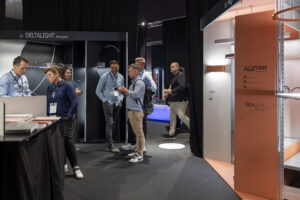 Besuchende stehen vor Messeständen.