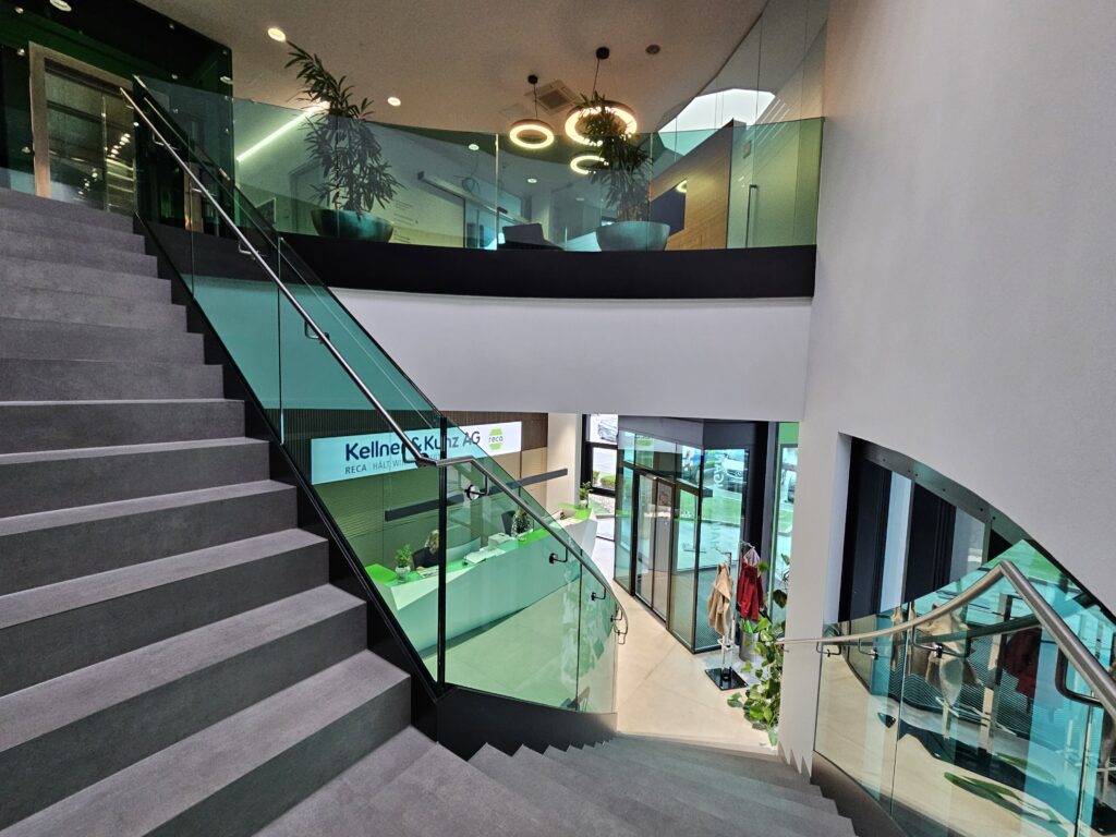 Ein modernes Nurglasgeländer in transparentem Grün mit gebogenen und geraden Abschnitten schmückt die Konzernzentrale von Kellner & Kunz in Wels und brachte Glas Krausmann den Sieg in der Kategorie Innenraum.