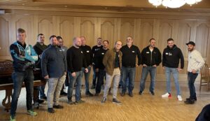 Kulturwandel in der Führungsetage. Viele Männer stehen in einem Veranstaltungsraum.