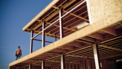 Ein Mann steht auf einem Holzbau und blickt hinunter.