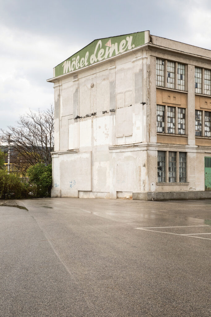 Ein leerstehendes Fabriksgebäude mit Parkplatzfläche davor.