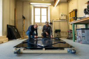 Zwei Männer arbeiten an einem Solarpanel.