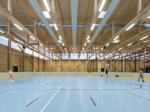 Turnsaal von innen: Blauer Boden und spielende Menschen.