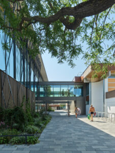 Schwimmhalle aus Holz mit Bäumen und viel Glas.